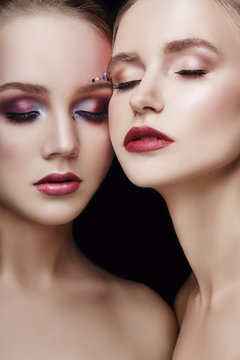 Art makeup two girls hugging, lots of rhinestones of different shapes, beautiful face smooth skin care. Beauty makeup on the face of two women close-up. Professional makeup artist, long beautiful hair