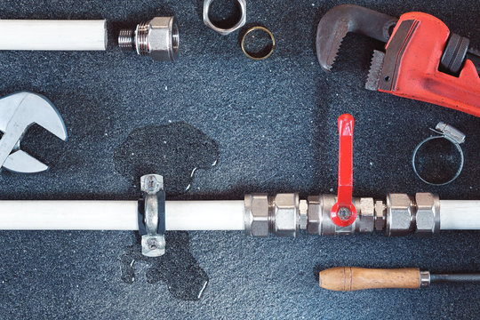 Plumbing concept. tools and pipes on a dark slate background.