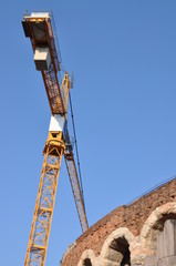 Fototapeta na wymiar Arena di Verona ancient wall amphitheater with construction crane against blue sky