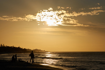 Evening beach at sunset with dark figures of fishermen