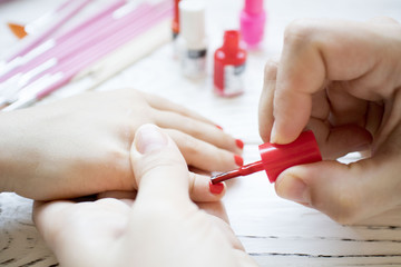 mom does baby manicure on white wooden table, beautiful nails