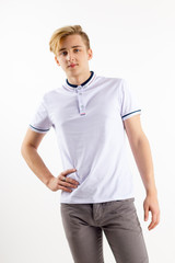 Fototapeta premium Handsome blond boy teenager in white shirt stands in white studio