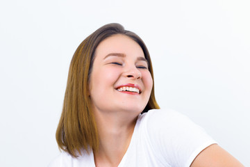 Pretty happy girl teenager in t-shirt laughs in white studio