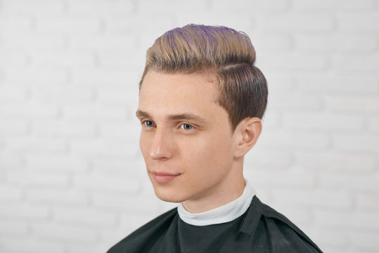 Young Boy Posing With Toned Lilac Hair On White Brick Background. Male Model Having Big Blue Eyes, Straight Nose, Small Ears.Having Perfect Hairdress, Modern, Stylish, Fashionable. Looking Forward.