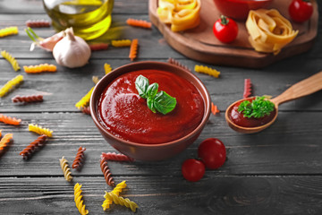Bowl with tasty tomato sauce on wooden table