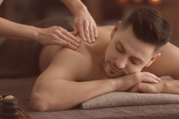 Obraz na płótnie Canvas Young man receiving massage at spa salon