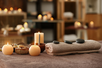 Obraz na płótnie Canvas Burning candles, towel and stones on massage table in spa salon