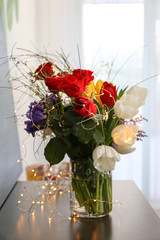 Vase with beautiful bouquet of flowers and garland as gift on table