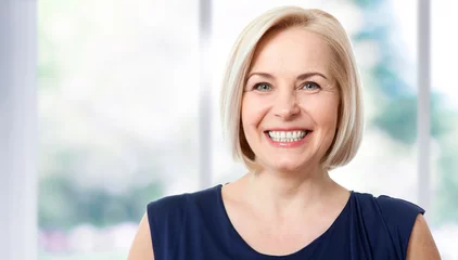 Fotobehang Attractive middle aged woman with a beautiful smile near the window. © missty