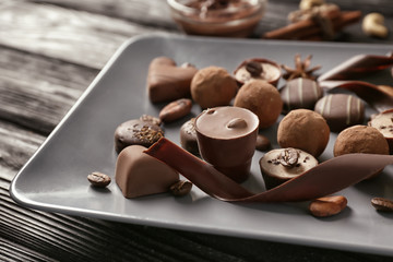 Plate with yummy chocolate candies on wooden table
