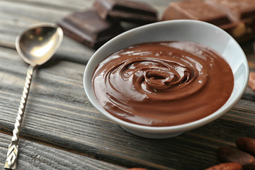 Bowl with molten chocolate on wooden table