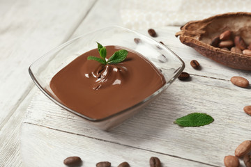 Glass bowl with molten chocolate on wooden table