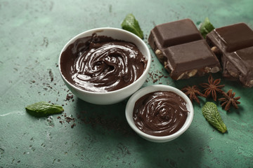 Bowls with molten chocolate on color background