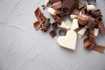 Pieces of chocolate with curls on light background