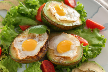 Eggs baked in avocado and fresh vegetables on plate, closeup