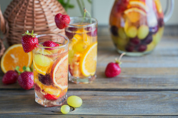 Homemade refreshing fruit sangria or punch with champagne, strawberries, oranges and grapes.