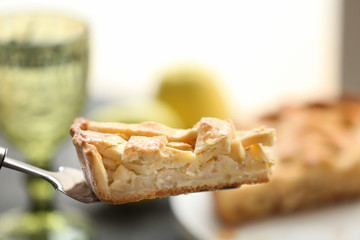 Spatula with piece of tasty apple pie on blurred background