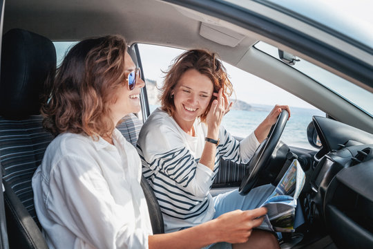 Two attractive friendly young women enjoying a day trip to sea, friends travel together concept