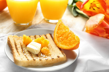 Tasty sweet toast with butter and pieces of orange on plate