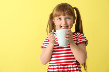 Cute little girl with cup of hot cocoa drink on color background