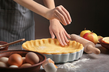 Woman preparing apple pie at table