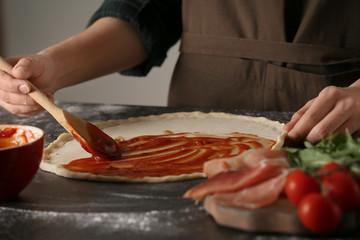 Woman preparing pizza at table in kitchen