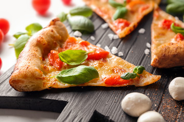 Board with slice of delicious pizza Margherita on table, closeup