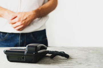 Man stand near concrete table with old telephone on white background. Communication concept. Copy space