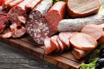 Assortment of delicious deli meats on wooden board