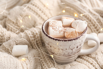 Cup of hot cocoa drink with marshmallows on warm plaid