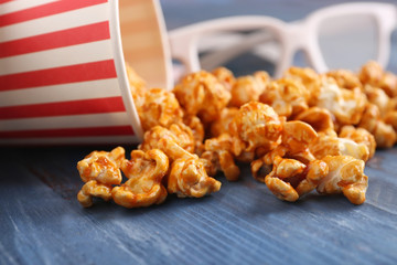Overturned cup with scattered caramel popcorn on table, closeup