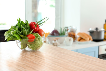 Bowl with fresh vegetables on table in kitchen