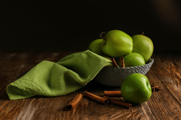 Bowl with fresh apples and cinnamon on wooden table