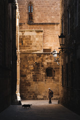BARCELONA, SPAIN - MARCH 19, 2018: Man and dog on a morning walk in the beautiful streets of the Gothic Quarter in Barcelona