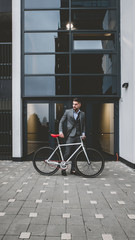 Handsome young adult man wearing suit riding his classic bicycle to work in the morning