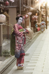 Maiko walking in an alley of Kyoto in the sunset light.