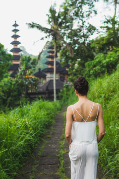 Young beautiful woman walking on Campuhan Ridge way of artists, in Bali, Ubud. Near traditional temple