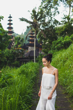 Young beautiful woman walking on Campuhan Ridge way of artists, in Bali, Ubud. Near traditional temple