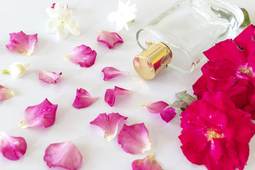 perfume bottle with rose flower, jasmine flower and petals on white background.