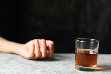 Man hand and transparent glass with alcohol on gray cement on black background
