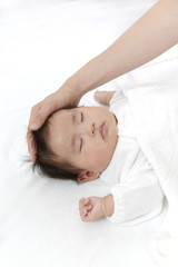 Fototapeta na wymiar 寝ている新生児に手を添え撫でる母の手