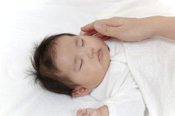 Obraz na płótnie Canvas 寝ている新生児に手を添え撫でる母の手