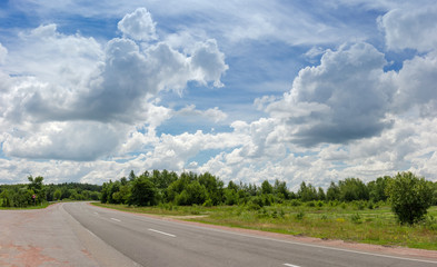Fototapeta premium Turn of the roadway among of forest against of sky