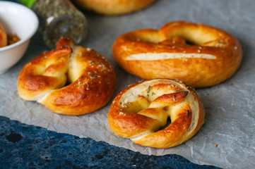 Traditional salted pretzels with oregano over blue stone background. Oktoberfest or beer snack concept.
