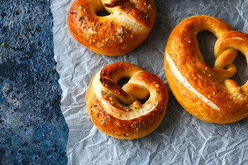 Traditional salted pretzels with oregano over blue stone background. Oktoberfest or beer snack concept.