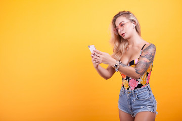 Woman Looking At Her Mobile with glasses over yellow background