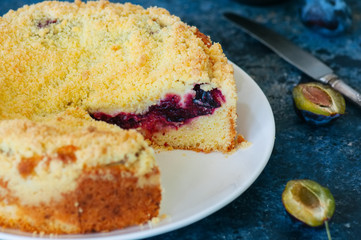  Corn flour crumble cake with plum jam filling served on a white plate. Blue stone baclground.