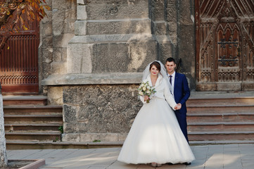 Romantic newly married couple posing by the ancient doors in an old town on their wedding day.