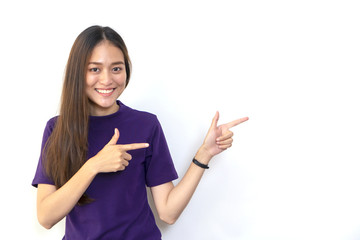 Beautiful young attractive Asian woman pointing to copy space, looking at camera and smiling.
