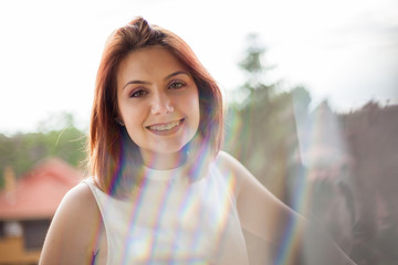 Portrait of gorgeous redhaired woman in summer rays at a balcony